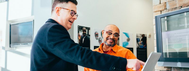 Man pointing to a screen showing co-worker something